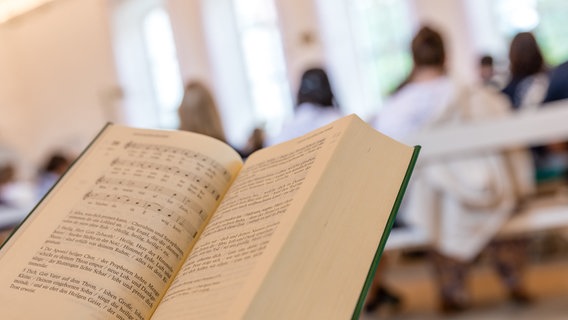 Eine Teilnehmerin eines Gottesdienstes hält ein Gesangbuch in der Hand. © picture alliance/dpa Foto: Frank Hammerschmidt