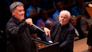 Alan Gilbert dirigiert im Vordergrund, Emanuel Ax spielt im Hintergrund Klavier. © SHMF/Felix König 