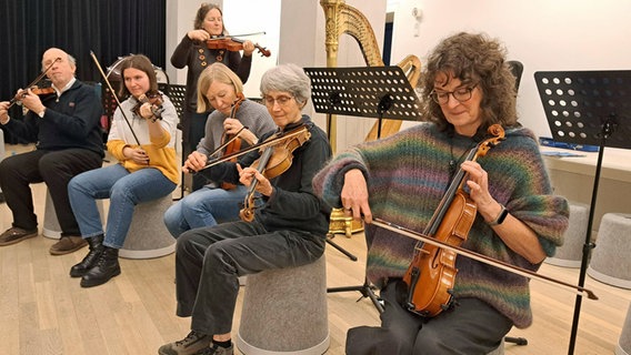 Ein Mann und fünf Frauen probieren sitzend und stehend Geigen aus. © NDR.de Foto: Petra Volquardsen