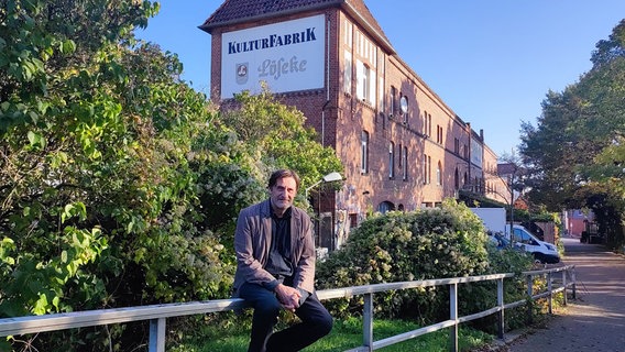 Das Gebäude der Kulturfabrik in Hildesheim. Davor sitzt ein Mann auf einem Geländer. © NDR Foto: Svenja Estner