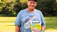 Der Verkäufer, Guido, hält die Ausgabe zum 30. Geburtstag des Asphalt-Magazins in der Hand. © Asphalt-Magazin Foto: Mario Biele