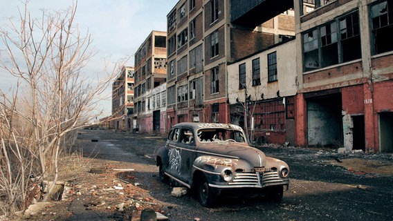 Ein Autowrack auf einem brach liegenden Fabrikgelände in Detroit. © Archäologisches Museum Hamburg Harburg 