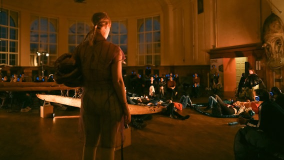 Visitors sit with headphones in a darkened room © Mo Poori 