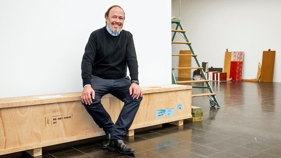 Ein bärtiger Mann (Galerist Alexander Schröder) sitzt auf einer langen Holzkiste. © Alexander Schröder / Hamburger Kunsthalle Foto: Romanus Fuhrmann