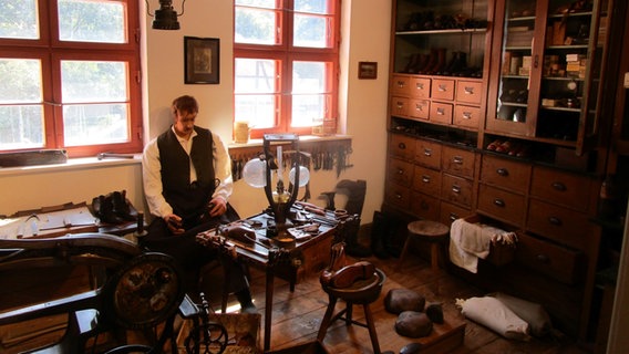 Eine lebensgroße Puppe eines Schusters sitzt in einer nachgestellten Schusterwerkstatt im Museum Hagenow. © NDR Foto: Axel Seitz