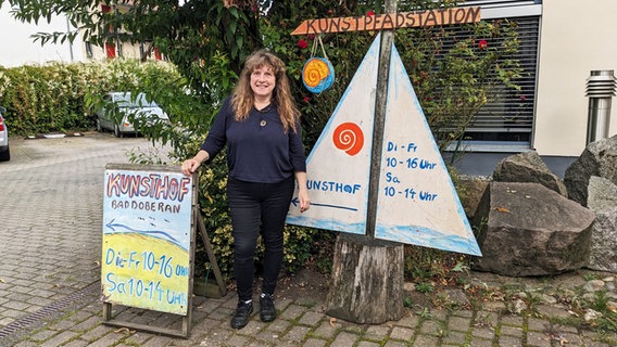 Eine Frau steht neben einem Schild, auf dem "Kunsthof" geschrieben steht © NDR Foto: Katja Bülow