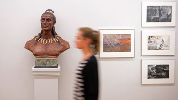 Eine Frau geht im Wilhelm Busch Museum für Karikatur und Zeichenkunst in der Ausstellung "Mit Karl May um die Welt" an einer Büste der Romanfigur Winnetou vorbei, 09.08.2013 in Hannover © dpa-Bildfunk Foto: Sebastian Kahnert/dpa