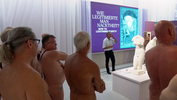 Nackte Männer hören in der Ausstellung "Unter Nackten" Kurator Andreas Urban zu. © NDR.de 