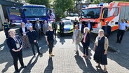 Museums- und ArchivmitarbeiterInnen stehen auf einem Platz und schauen in die Kamera. Im Hintergrund ein Lkw des THW, ein Polizeiwagen und ein Feuerwehrwagen. © Landesmuseum Natur und Mensch Oldenburg Foto: Torsten von Reeken