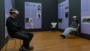 Ein Schüler und eine Schülerin sitzen mit VR-Brille in einer Ausstellung. © Landesmuseum Hannover 