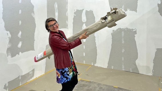 Frau mit Papprolle steht in einer Ecke. © NDR Foto: Frank Hajasch