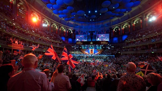Menschen schwenken Flaggen während der "Last Night of the Proms 2014" in der Royal Albert Hall. © picture alliance / dpa | Will Oliver Foto: Will Oliver