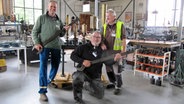 Drei Männer posieren vor technischen Geräten; zwei von ihnen halten riesige Schrauneschlüssel wie Gitarren in der Hand. © NDR Foto: Jens Zacharias