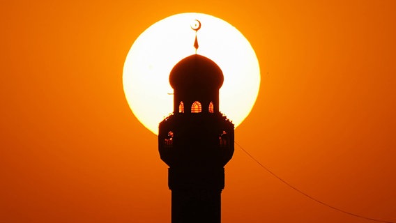 Minarett einer Moschee mit Sonne im Hintergrund © imago 