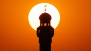 Minarett einer Moschee mit Sonne im Hintergrund © imago 