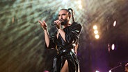 Die Musikerin Conchita Wurst mit Zöpfen und dunkler Lederkleidung singt auf der Bühne © Annette Riedl/dpa +++ dpa-Bildfunk +++ Foto: Annette Riedl