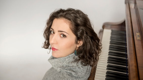 Lilit Grigoryan sitzt auf dem Fußboden und lehnt sich an ein Klavier © Neda Navaee 