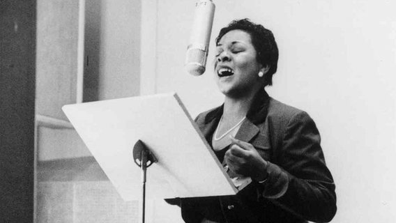 Eine Frau singt mit geschlossenen Augen in ein Mikrofon. © Universal Music Jazz/Herman Leonard Foto: Herman Leonard