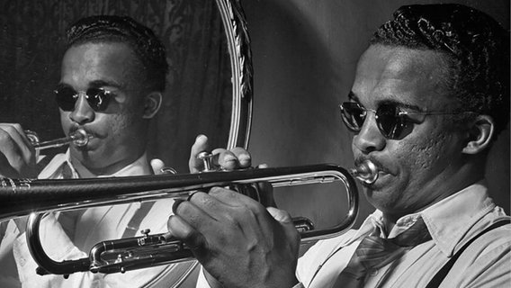 Howard McGhee spielt vor einem Spiegel Trompete. © IMAGO / UIG 