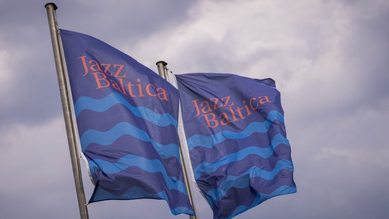 Zwei Flaggen im der AUfschrift JazzBaltica flattern vor einem wolkenverhangenen Himmel © John Garve 