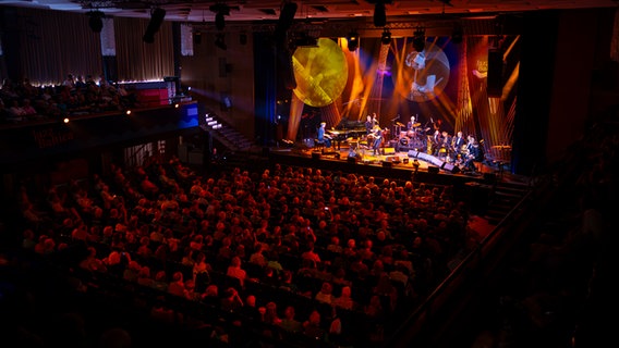 Musiker spielen vor Publikum auf einer großen ausgeleuchteten Bühne in einer Halle. © Felix Koenig Foto: Felix Koenig