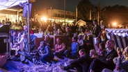 Ein Gruppe von Menschen vor eine Bühne am Strand. © Felix Koenig Foto: Felix Koenig