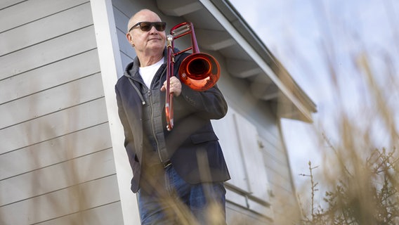 Nils Landgren mit roter Posaune sitzt im Sessel, um ihn herum die Funk Unit © Felix König 