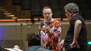 Alex Paxton im Gespräch mit Musikern im Orchester © NDR.de 