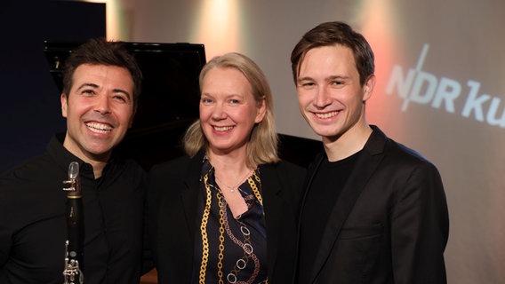 Eine Frau steht zwischen zwei jungen Männern und alle lachen herzlich. © Franziska Dieckmann / NDR Foto: Franziska Dieckmann / NDR