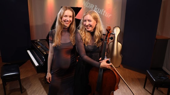 Zwei junge Frauen stehen lächelnd nebeneinander. EIne von ihnen hält ein Cello in der Hand. © Ekaterina Shurygina / NDR Foto: Ekaterina Shurygina / NDR