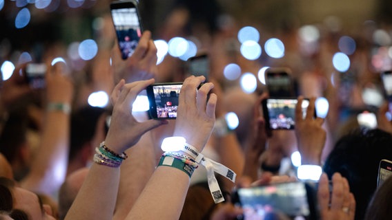 Viele Hände im Stadion halten Mobiltelefone hoch und filmen ein Konzert (von Taylor Swift) © dpa Foto: Marius Becker