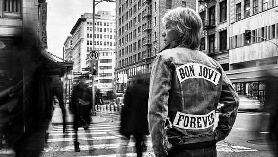 Der Sänger Jon Bon Jovi steht mit dem Rücken zur Kamera. Auf seiner Jeansjacke steht: Bon Jovi forever. © Universal Music/dpa Foto: Universal Music/dpa