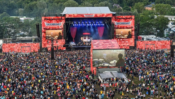 Zuschauer stehen auf einem Festival-Gelände vor einer Bühne. © picture alliance/dpa | Foto: Lars Penning