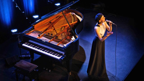 Anna Depenbusch singt auf der Bühne und steht vor einem Konzerflügel © Linde Sobkowiak Foto: Linde Sobkowiak