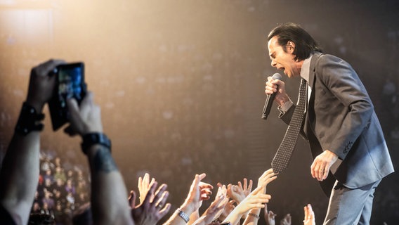 Nick Cave singt am Bühnenrand während ihm Fans Arme entgegenstrecken. © picture alliance / Gonzales Photo/Terje Dokken | Gonzales Photo/Terje Dokken Foto: Terje Dokken