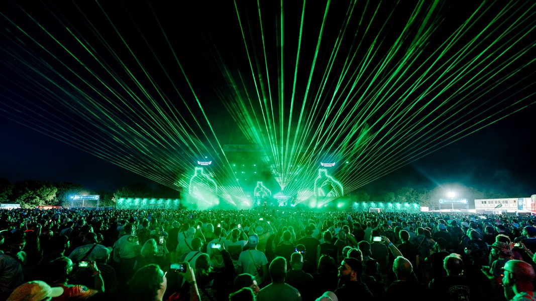 Eine Lasershow mit grünen Lichtern vor einem großen Festivalpublikum.