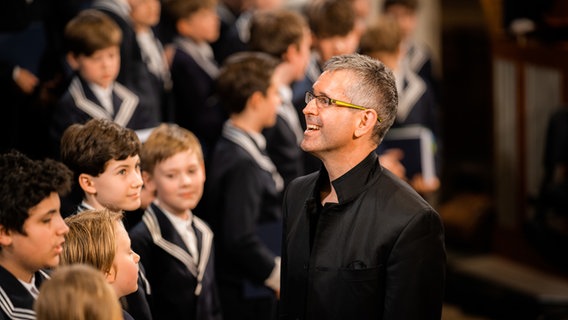 Der Thomanerchor und Andreas Reize stehen sich im Profil gegenüber © THOMANERCHOR Leipzig Tom Thiele 