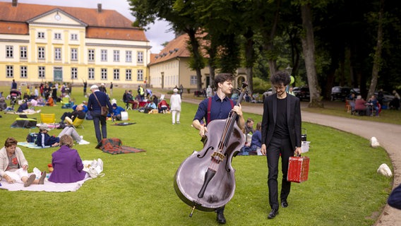 Zwei Musiker laufen mit ihren Instrumenten über eine Wiese © Felix König / SHMF 