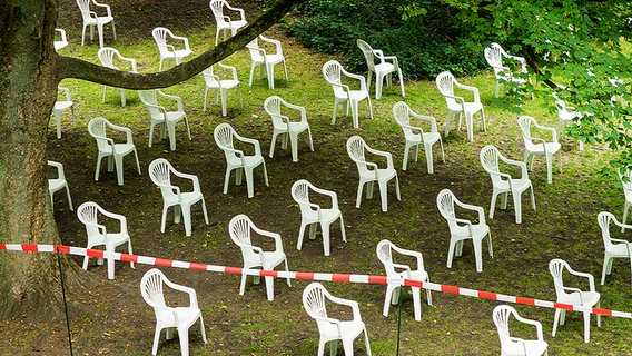 Viele weiße Kunststoffstühle stehen auf einem grünen Rasen. © Karo Streifen / Photocase Foto: Karo Streifen