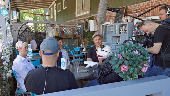 Die Stoffpuppe Werner Momsen sitzt am Tisch mit den vier Musikern der Band Godewind. © Lornz Lorenzen Foto: Lornz Lorenzen