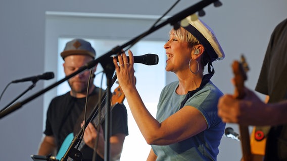 Eine Musikerin mit Matrosenmütze auf dem Kopf singt auf der Bühne. © Lornz Lorenzen Foto: Lornz Lorenzen