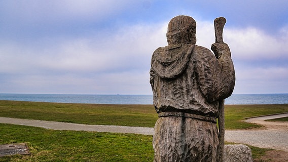 Eine Mönchsfigur in Puttgarden (Fehmarn), am Horizont das Meer © picture alliance / Zoonar Foto: HGVorndran