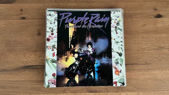 Das Cover der Platte "Purple Rain" von Prince liegt auf einem Tisch. © Warner Bros. Records 