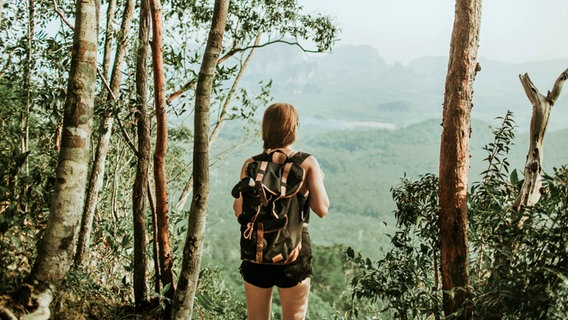 Eine Backpackerin steht im Urwald © picture alliance / Shotshop Foto: Addictive Stock