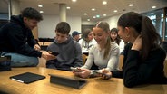 Schülerinnen und Schüler betrachten ihre Smartphones auf den Klassenbänken © NDR.de 