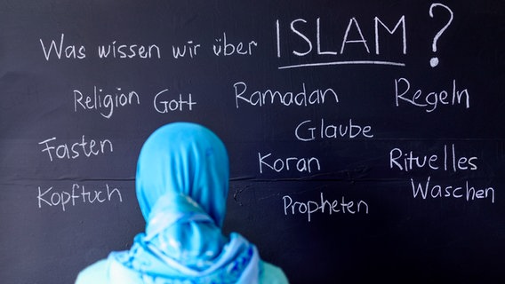 Ein Mädchen mit einem blauen Kopftuch steht an der Tafel auf der Begriffe stehen, die zum Wort "Islam" passen. © picture alliance / Geisler-Fotopress | Dwi Anoraganingrum/Geisler-Fotop 