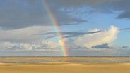 Sandstrand und Himmel mit Regenbogen. © picture alliance / imageBROKER | Foto: Michael Narten