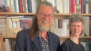 Joachim Dicks und Lisa Kreißler stehen vor einer Bücherwand und lächeln. © NDR Foto: Birgit Bohle
