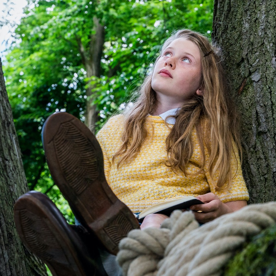 Ein Mädchens sitzt auf einem Baum. © LOOKSfilm 