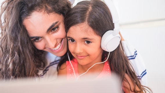 Teenagerin und ihre kleine Schwester mit Laptop und Kopfhörern. © photocase.de Foto: Westend61